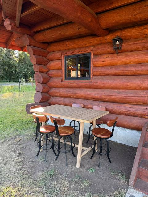 Terraza bajo el alero, con mesa alta y pisos de madera