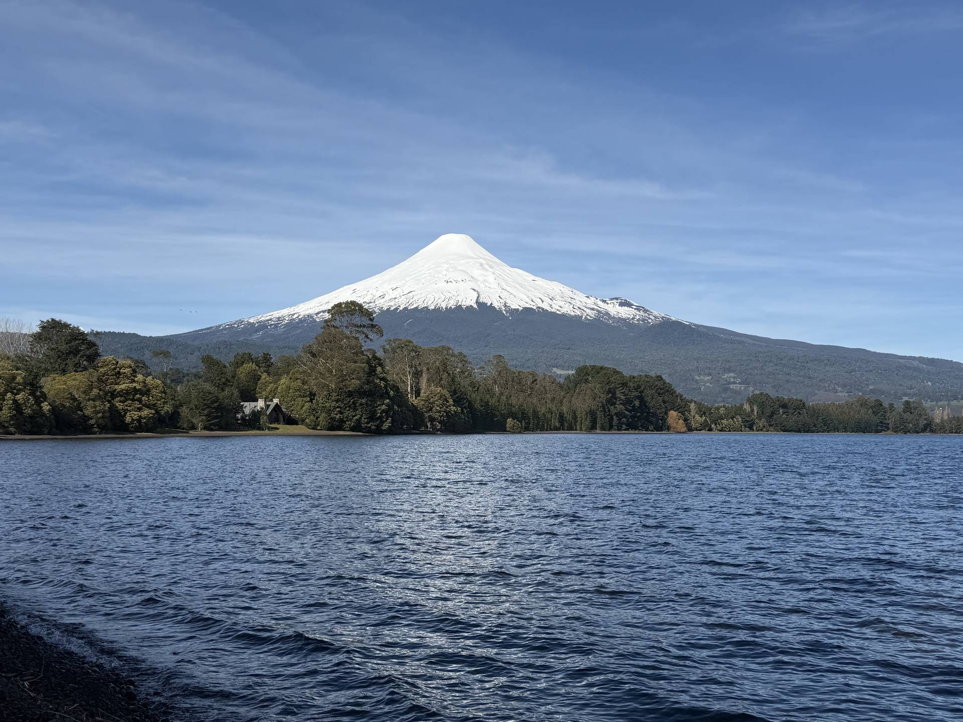 El volcán Osorno nevado sobre el lago Llanquihue, con bosque en la orilla